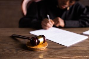 Judge signing papers with a gavel in the foreground, representing the False Claims Act and class actions and Fresenius Whistleblower retaliations