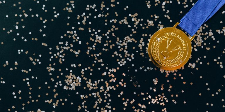 Close-Up Shot of a Gold Medal on a Black Surface