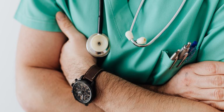 Crop doctor with stethoscope in hospital, representing healthcare ads.