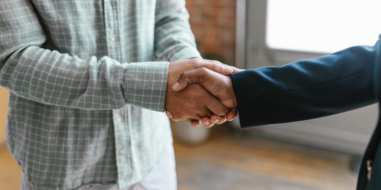 A Person in Green Plaid Long Sleeve Shirt Shaking Hands with Person in Black Blazer, representing SEC Whistleblowers or FCPA Enforcement Action