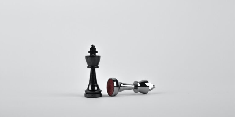 Battle - Two Silver Chess Pieces on White Surface