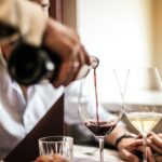 Crop man pouring red wine in glass in restaurant