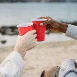 People Touching Red Solo Cups Together on a Beach