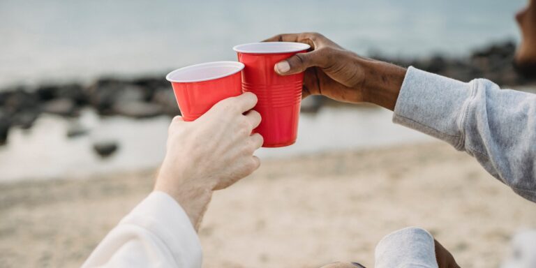 People Touching Red Solo Cups Together on a Beach