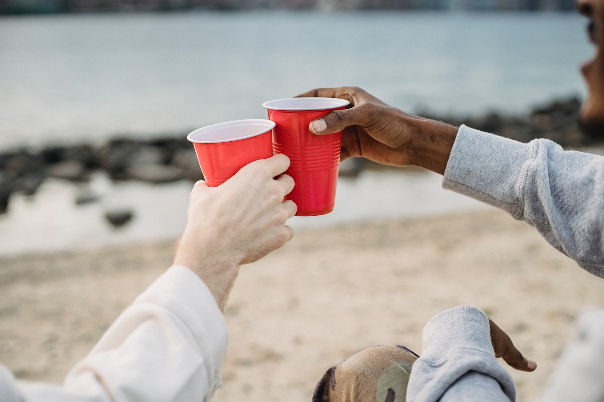 People Touching Red Solo Cups Together on a Beach