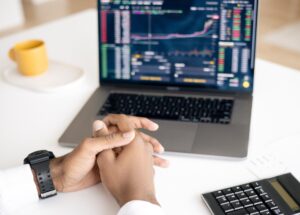 A person with hands folded in front of computer, representing high speed trading