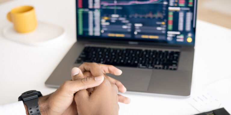 A person with hands folded in front of computer, representing high speed trading