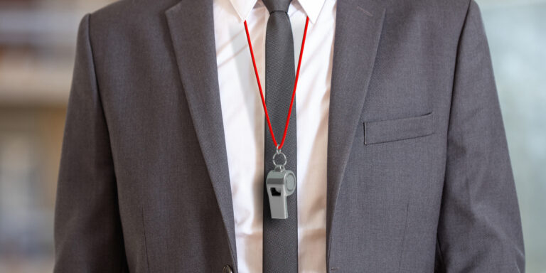 Man in suit wearing a whistle with red string, representing famous whistleblowers